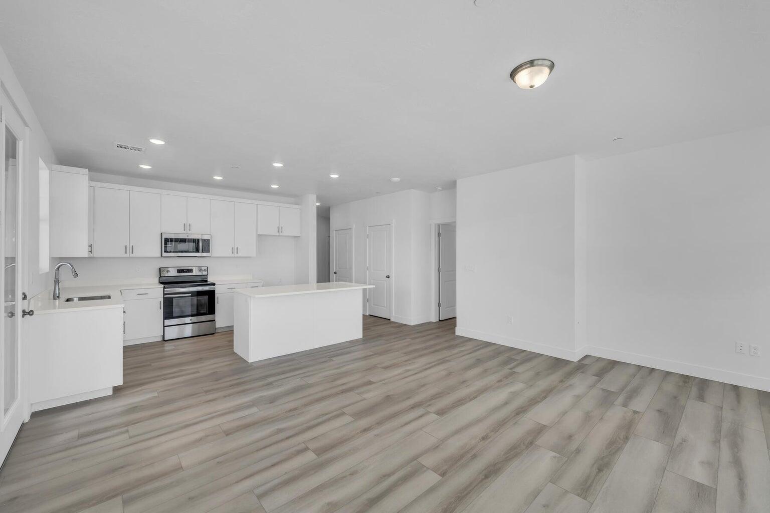 Kitchen featuring appliances with stainless steel finishes, light countertops, a kitchen island, white cabinets, and light wood finished floors