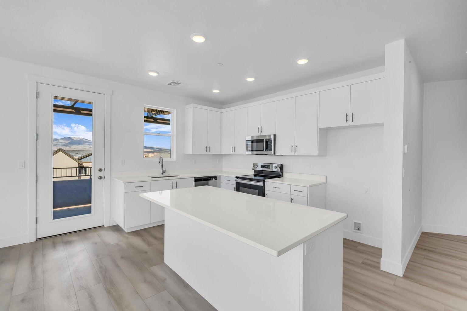 Kitchen with a kitchen island, appliances with stainless steel finishes, light countertops, light wood-style flooring, and recessed lighting