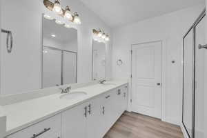 Bathroom with a shower stall, double vanity, and wood finished floors