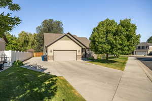 View of front of home with driveway, stone siding, a garage, and roof with shingles