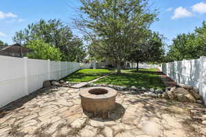 Fenced backyard featuring an outdoor fire pit and a patio