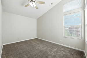 Spare room with plenty of natural light, lofted ceiling, carpet, and a ceiling fan
