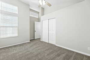 Unfurnished bedroom with carpet, a closet, high vaulted ceiling, and a ceiling fan