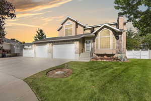View of front of property with concrete driveway, a gate, brick siding, and a chimney