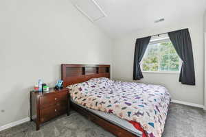 Carpeted bedroom with attic access and lofted ceiling