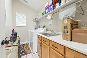 Laundry room with independent washer and dryer, light tile patterned floors, and cabinet space