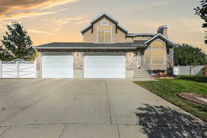 Traditional home with a gate, a chimney, concrete driveway, and a shingled roof