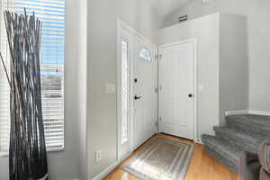 Entryway with wood finished floors and vaulted ceiling
