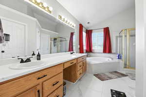 Full bath with vaulted ceiling, double vanity, a shower stall, a garden tub, and marble finish flooring
