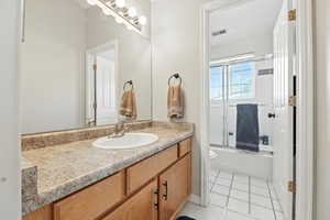 Full bath with vanity, tile patterned flooring, and enclosed tub / shower combo