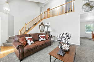 Living area featuring a high ceiling, stairs, and carpet floors