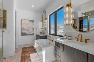 Bathroom featuring two vanities, a freestanding bath, and recessed lighting