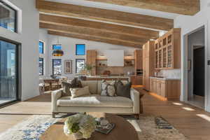 Living area featuring light wood finished floors, beam ceiling, and high vaulted ceiling