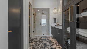 Bathroom featuring a stall shower, vanity, and marble look tile flooring
