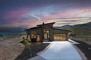 Contemporary home featuring a garage, a mountain view, stone siding, concrete driveway, and a metal roof