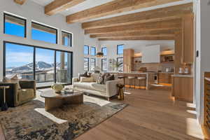 Living area with wood-type flooring, a towering ceiling, beam ceiling, and a mountain view