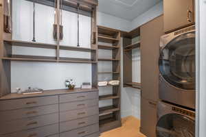 Washroom featuring stacked washer / drying machine, cabinet space, and light tile patterned floors