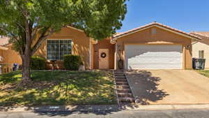 View of front facade with stucco siding, a tile roof, an attached garage, and concrete driveway