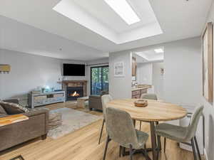 Dining space featuring a tray ceiling, light wood-style flooring, and a stone fireplace