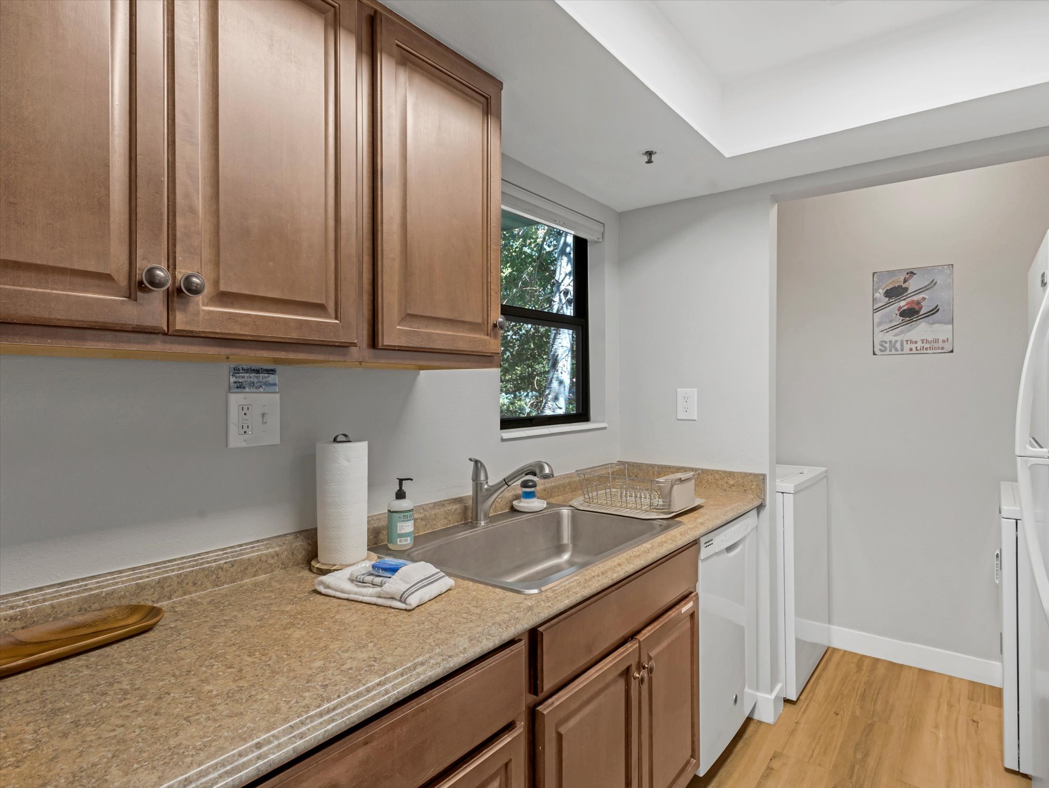 Kitchen featuring light wood-type flooring, washer / clothes dryer, white appliances, and light countertops