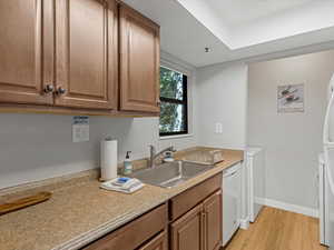 Kitchen featuring light wood-type flooring, washer / clothes dryer, white appliances, and light countertops