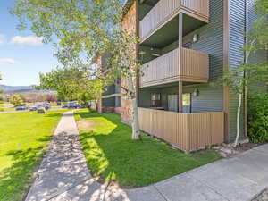 View of side of home with a balcony and a lawn