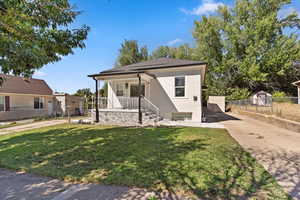 View of front of property featuring covered porch, concrete driveway, and stucco siding