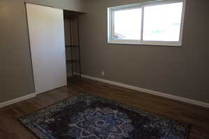 Unfurnished bedroom with wood finished floors and a closet