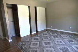Unfurnished bedroom with wood finished floors and multiple closets