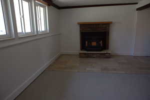 Unfurnished living room featuring ornamental molding, light tile patterned floors, and a wood stove