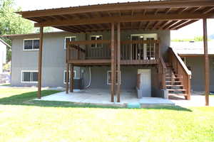 Back of house featuring a patio, stairs, brick siding, a lawn, and a deck