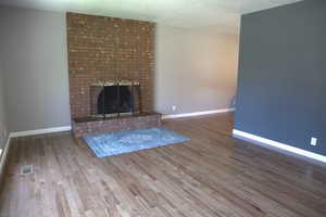 Unfurnished living room featuring wood finished floors, a fireplace, and a textured ceiling