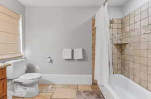 Full bathroom with vanity, stone tile flooring, and shower / bath combo