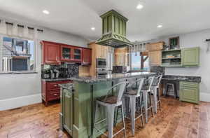 Kitchen with green cabinetry, light wood-type flooring, a kitchen island, and recessed lighting