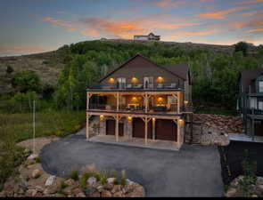 View of front of property with a balcony, asphalt driveway, stone siding, and stairway