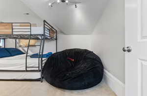 Carpeted bedroom featuring vaulted ceiling