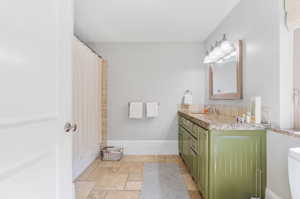 Full bathroom featuring double vanity and stone finish flooring
