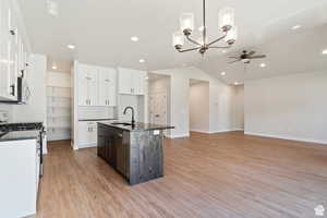 Kitchen featuring appliances with stainless steel finishes, vaulted ceiling, dark countertops, a chandelier, and backsplash
