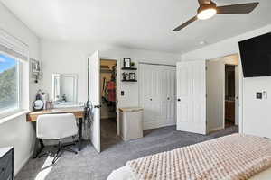 Bedroom featuring carpet, an office area, a textured ceiling, ceiling fan, and two closets
