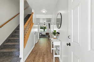 Foyer with wood finished floors, a ceiling fan, and stairway