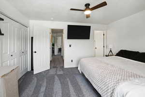 Bedroom featuring dark colored carpet, a closet, a textured ceiling, and ceiling fan