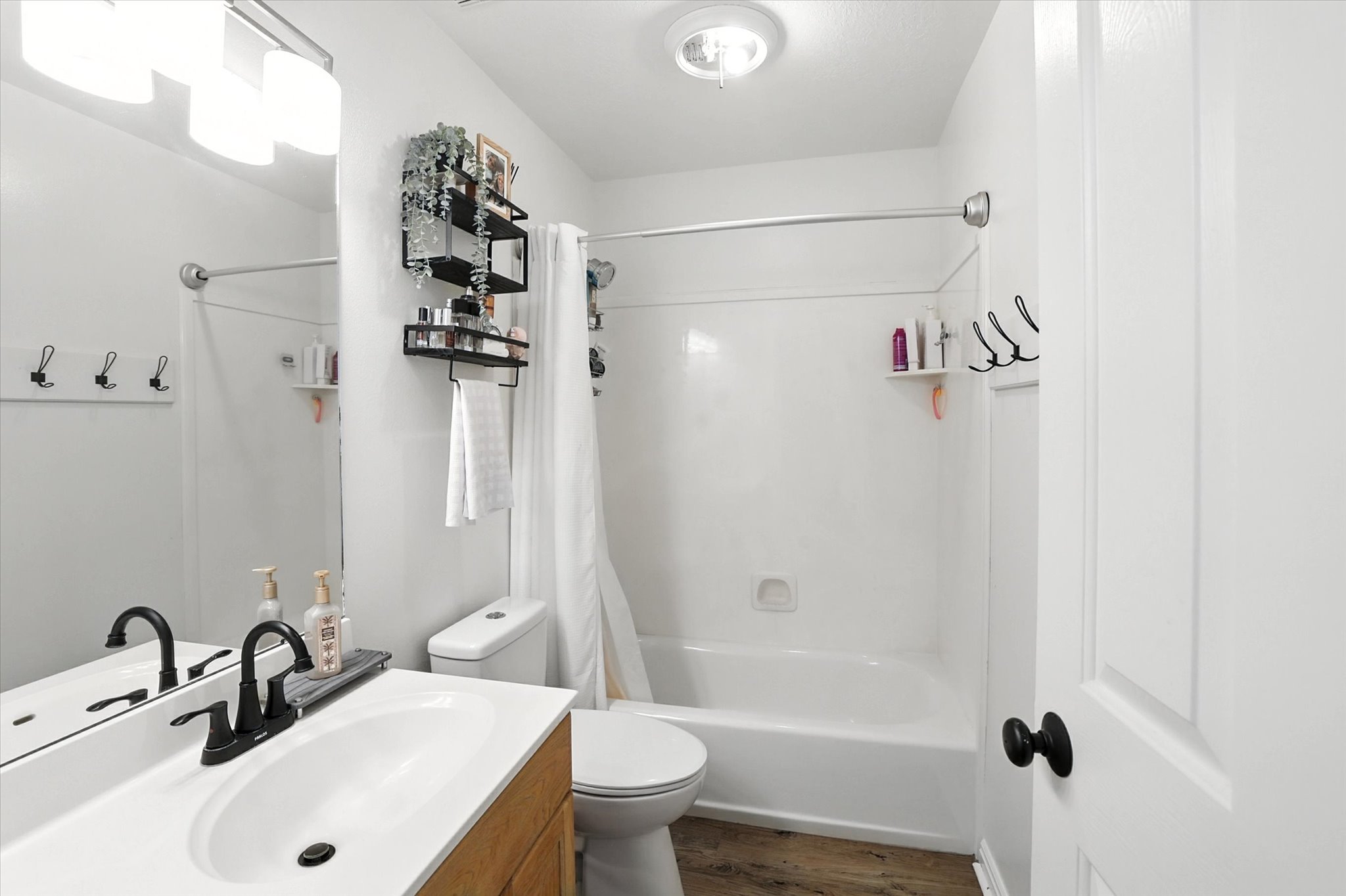 Full bath with vanity, shower / bath combo, and wood finished floors