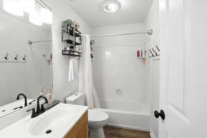 Full bath with vanity, shower / bath combo, and wood finished floors