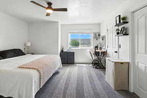 Carpeted bedroom featuring a textured ceiling and a ceiling fan