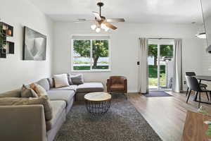 Living room featuring healthy amount of natural light, wood finished floors, a ceiling fan, and a textured ceiling