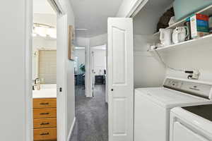 Laundry room featuring washing machine and dryer, carpet, a textured ceiling, and attic access