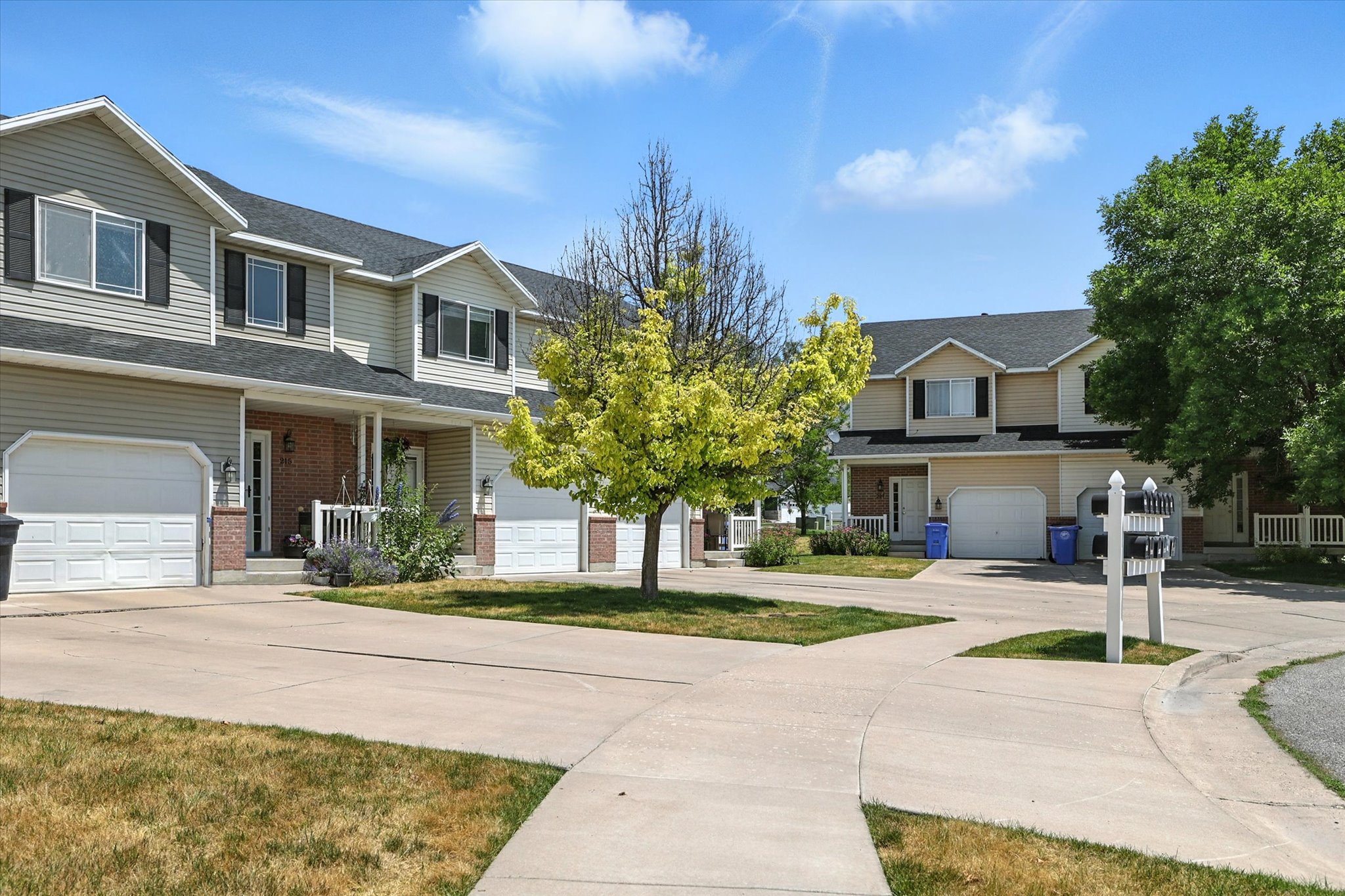 View of front of home featuring a porch, brick siding, concrete driveway, and roof with shingles