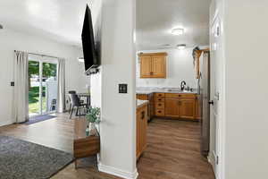 Bar area featuring dark wood finished floors, a textured ceiling, and freestanding refrigerator
