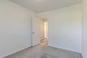 Spare room featuring baseboards and light colored carpet