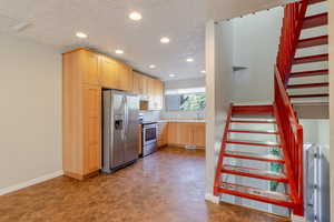 Kitchen with light brown cabinets, stainless steel appliances, light countertops, a textured ceiling, and recessed lighting